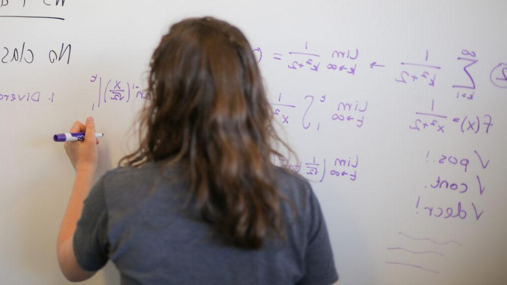 Student doing math problems on a whiteboard