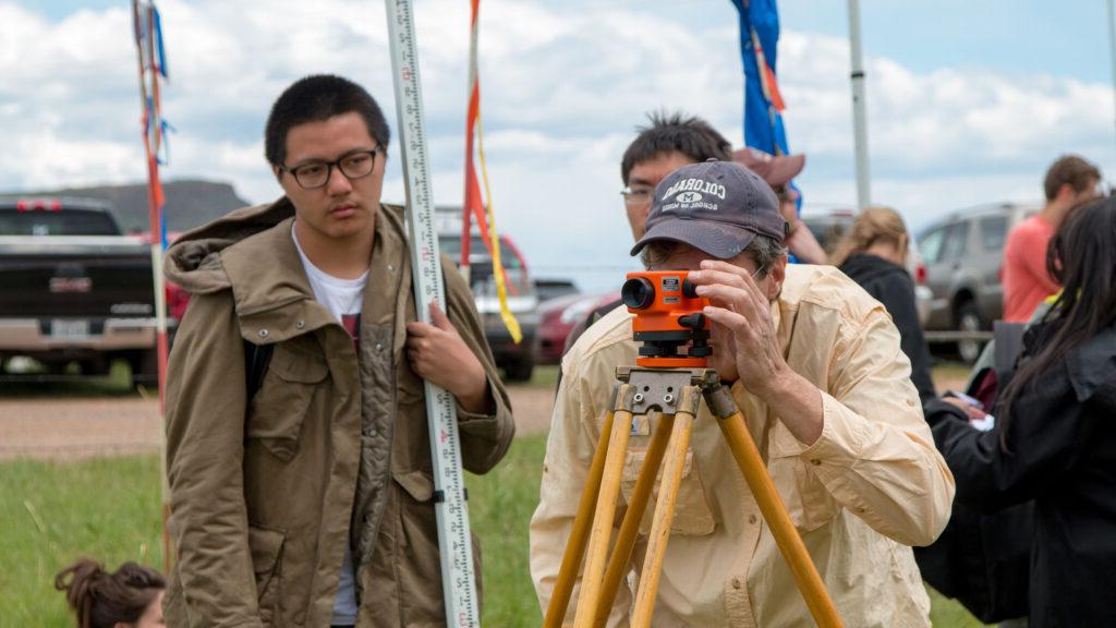 Civil engineering students working with a camera-type device during their field session